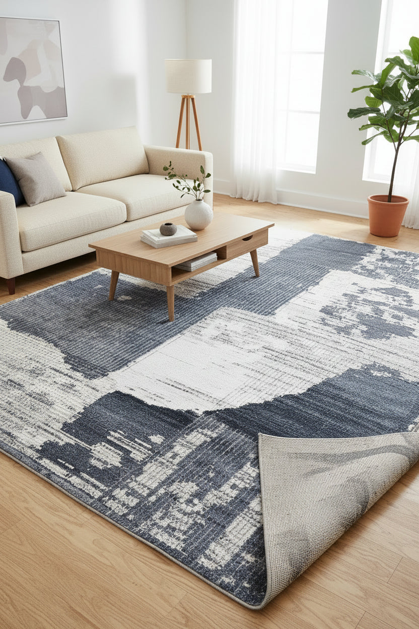 An abstract area rug with a distressed, textured block pattern in slate blue, navy, and off-white.