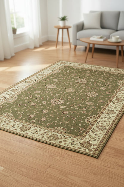 An area rug with an intricate traditional floral pattern, featuring a dark olive green center field and a wide cream-colored border with detailed floral motifs.