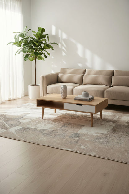 An abstract area rug with a distressed geometric pattern in shades of taupe, beige, gray, and off-white.