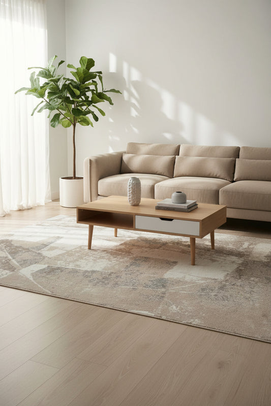 An abstract area rug with a distressed geometric pattern in shades of taupe, beige, gray, and off-white.