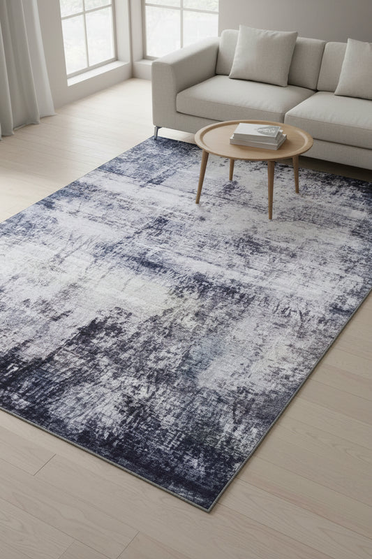 An abstract distressed rug with a textured, vintage pattern in shades of slate blue, navy, charcoal gray, and off-white.
