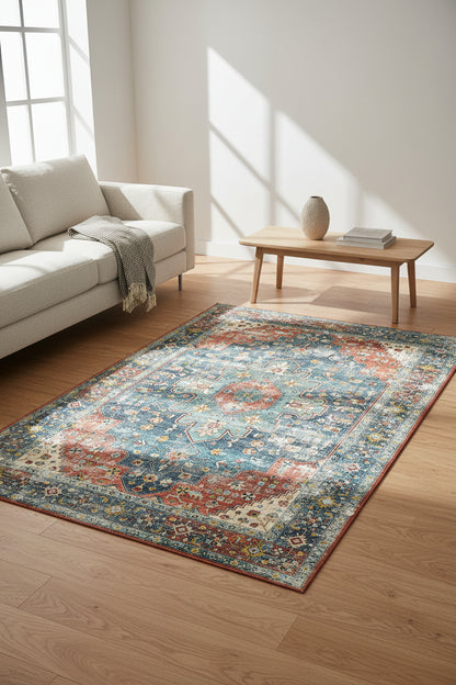 A distressed traditional area rug with an ornate central medallion and floral motifs, featuring a color palette of dusty blue, terracotta red, cream, and beige.