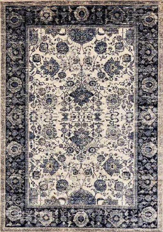 A rectangular area rug with an ornate traditional floral pattern, featuring a cream center field and a dark navy blue border.