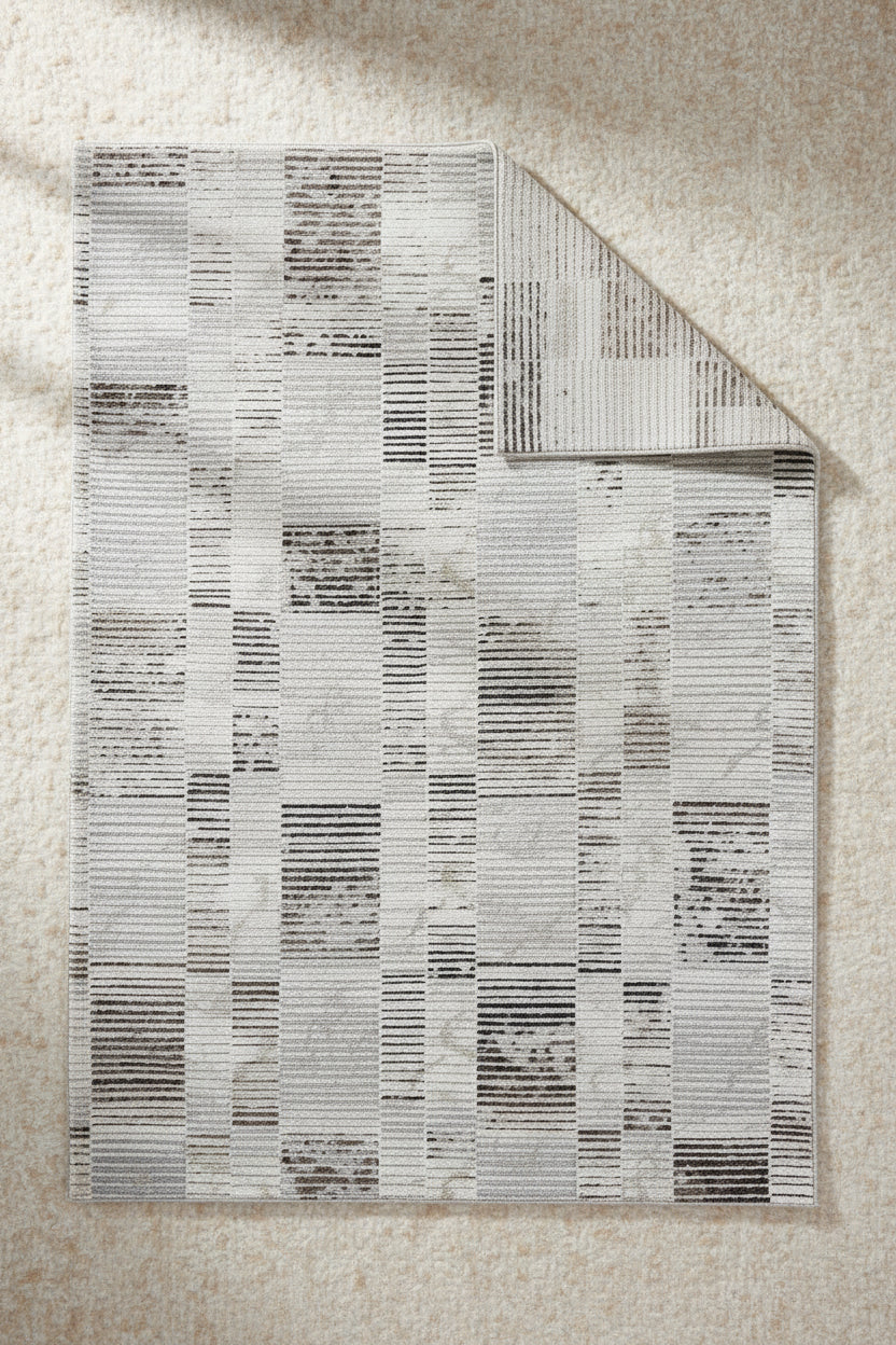 A square area rug featuring a modern abstract striped pattern in shades of off-white, light gray, beige, and charcoal.